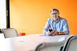 © Westend61 - Smiling male professional with mobile phone at desk in board room