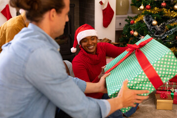 Wall Mural - Happy diverse female and male friends sharing presents at christmas time