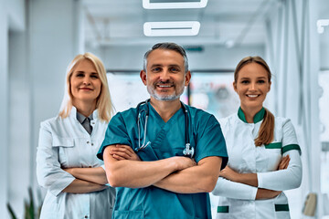 Smiling medical team with arms crossed in the hallway.