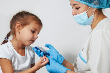 Wall Mural - Young nurse doctor measuring blood sugar level of girl