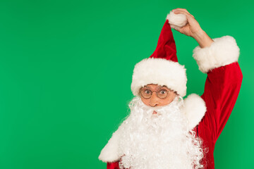 Bearded santa claus in eyeglasses holding hat isolated on green