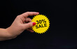 a woman's hand holds a yellow sticker with the inscription discount, a layout on the theme of Black Friday.