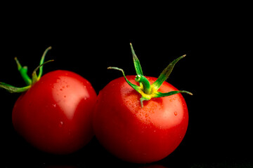 Wall Mural - Two red cherry tomatoes on a black background, tomatoes with water droplets close-up view. Healthy eating concept photo