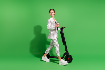 Poster - Photo of charming sweet woman dressed checkered clothes walking kick scooter looking empty space isolated green color background