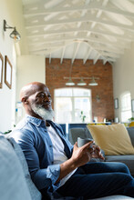 Happy Senior African American Man In Living Room Sitting On Sofa, Holding Mug