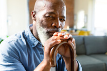 Portrait Of Thoughtful Senior African American Man In Living Room Holding Walking Cane