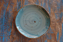 A Blue Turquoise Ceramic Bowl On A Rustic Wood Table With Blue Paint Remnants Seen Directly From Above