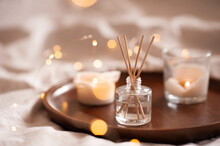 Home Perfume In Glass Bottle With Wood Sticks, Scented Burn Candles  Tray In Bedroom Close Up. Aromatherapy Cozy Atmosphere Lifestyle. Winter Warm Xmas Season.