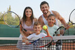 © New Africa - Happy family with tennis rackets on court outdoors