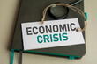 © Maks_Lab - on the notebook is a magnifying glass and paper card with the inscription economic crisis
