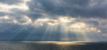 The Sun Breaks Through The Clouds Illuminating The Sea With Its Rays 
