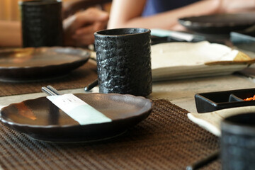 Wall Mural - Close-up shot of the black ceramic plates and cups on a table at a restaurant