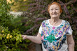 © galitsin - elderly woman against background of flowers in botanical garden with her beloved fruit