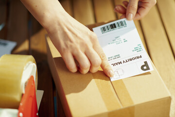 modern female in warehouse applying shipping label to parcel