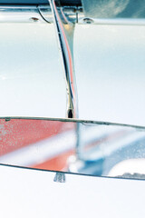 A vertical image of an isolated retro vintage rearview mirror in a vehicle.