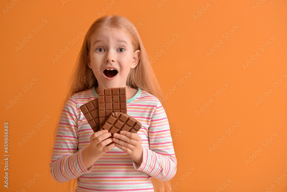 Surprised little girl with chocolate on color background