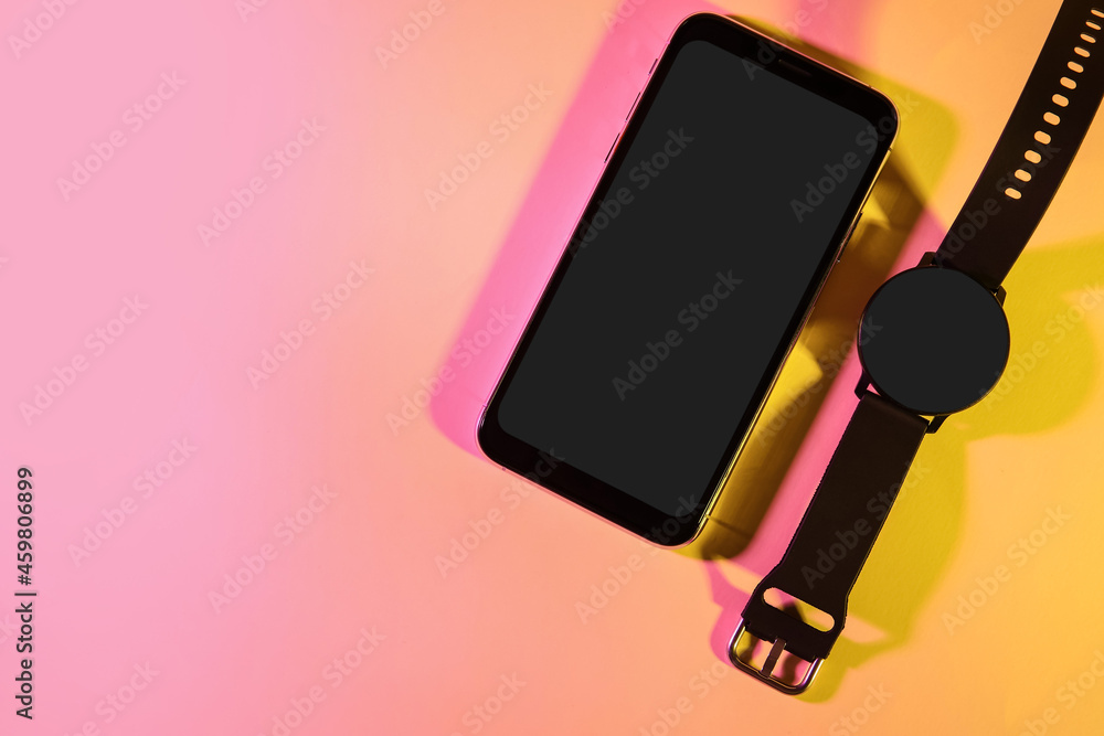 Modern mobile phone and smart watch on color background