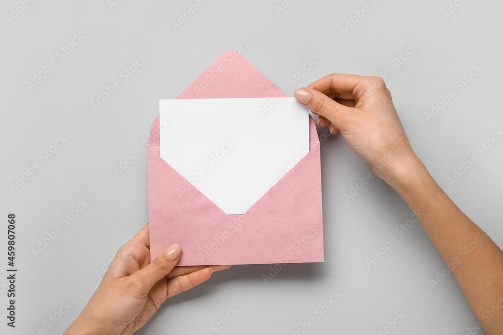 Female hands with envelope and blank card on light background