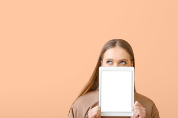 Beautiful young woman holding tablet computer with blank screen on color background