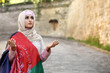 Praying Muslim woman with flag of Afghanistan on city street