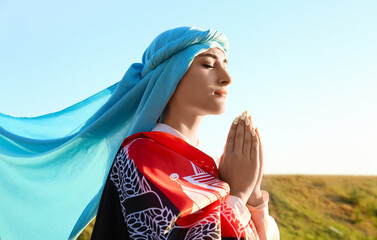 Praying Muslim woman with flag of Afghanistan outdoors