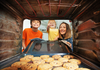 Boy point to the cookies tray in oven, with family