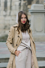 Wall Mural - Portrait of fashionable women in beige sports suit and trench coat posing on the street