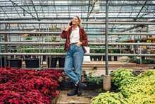 Smiling Female Farmer With Hand In Pocket Talking On Mobile Phone At Plant Nursery