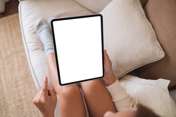 Top view mockup image of a woman holding digital tablet with blank desktop screen on sofa at home