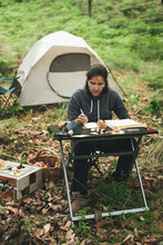 Pensive Woman Sitting At Table And Researching Mushroom In Forest