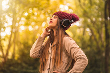 Young Woman Listening To Music In Autumn Park