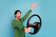 © deagreez - Profile side photo of young amazed crazy guy riding car fast speed extreme riding wheel isolated on blue color background