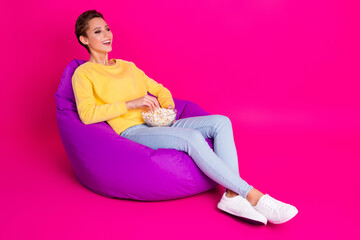 Sticker - Photo of adorable shiny young woman dressed yellow pullover sitting bean eating pop corn smiling isolated pink color background