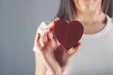 woman holding wooden red heart