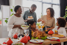 African American Grandparents Holding Food Near Family And Thanksgiving Dinner