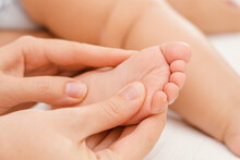 Mom Gently Massages The Feet Of A Sleeping Baby