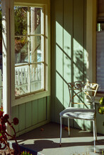 Sunny Window Casts Light And Shadows Across Patio Porch With Vintage Metal Chair