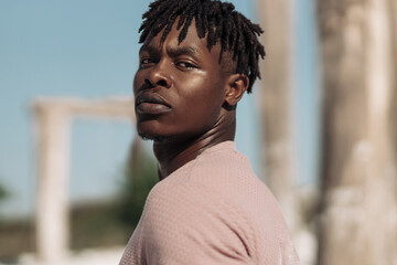 Portrait of handsome black african man, with afro hairstyle, model in stylish clothes posing outdoors