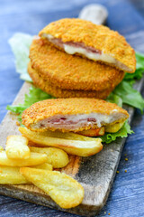 Wall Mural - 
 Crispy  deep fried home made     chicken Cordon bleu with cheese   and ham  and french fries on wooden rustic background.  