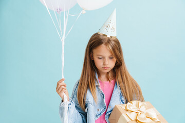 white sad girl posing with gift box and multicolored balloons