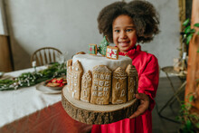 Girl Holding Christmas Gingerbread Cake At Home