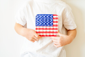 Sensory Fidget Toy in the form of American flag in a child hands on white background. Pop It. Anti stress toy.