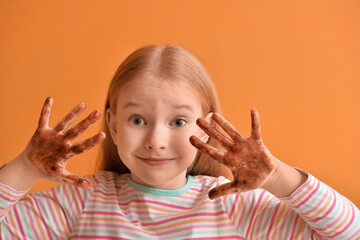 Sticker - Cute little girl with chocolate on hands against color background, closeup