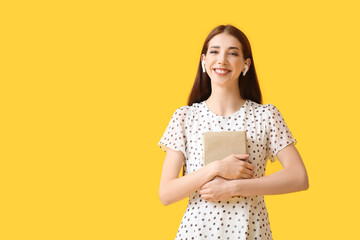 Wall Mural - Young woman with earphones and book on color background