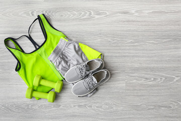 Wall Mural - Sportswear, shoes and dumbbells on light wooden background