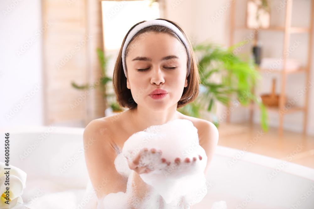 Young woman taking relaxing bath with foam at home