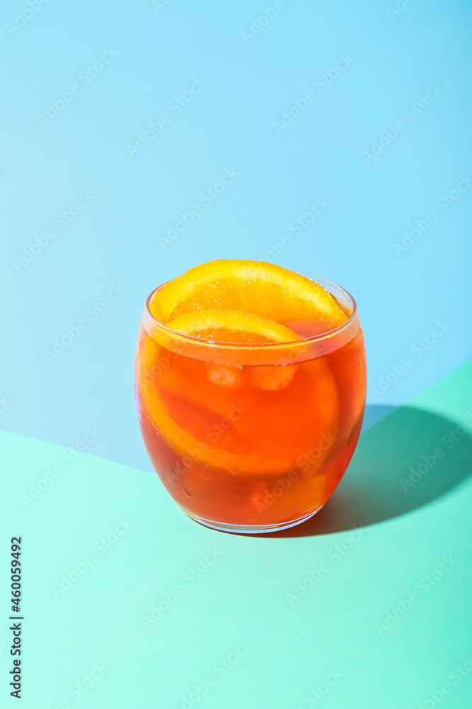 Glass of Aperol spritz cocktail on color background