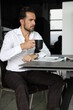Poranna prasa i praca podczas pierwszej kawy. Przystojny mężczyzna w białej koszuli pije poranną kawę. 