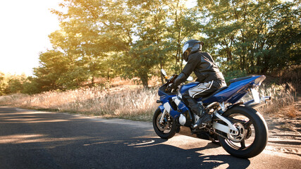 Beautiful motorcycle riding on a forest road. Have fun driving an empty road on a motorcycle ride in the warm sunbeams of the sunset.