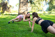 © luisrojasstock - two young caucasian girls practicing push-ups and hit hands in a park on a sunny day